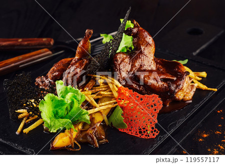 Grilled quails served on stone plate with potatoes and mushrooms 119557117