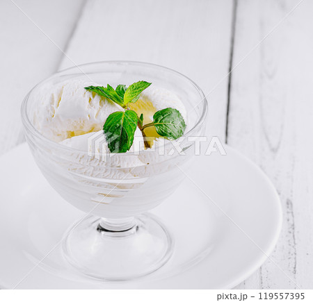 White ice cream decorated with mint leaves being served on white table 119557395