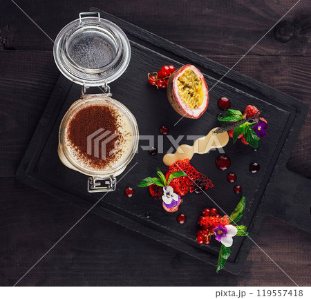 Delicious tiramisu served in jar on black slate with strawberries and passion fruit 119557418