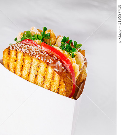 Delicious toasted sandwich with chicken and vegetables in white cardboard box on white background 119557419