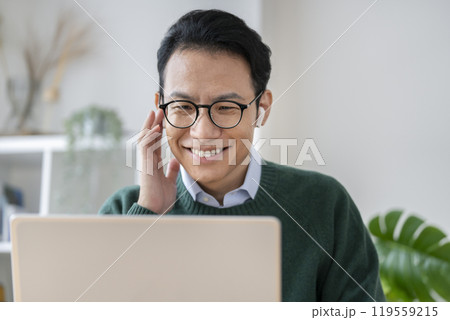ノートパソコンでオンラインミーティングをするイヤホンをつけた30代後半の男性 ノートパソコンでオンラインミーティングをするイヤホンをつけた30代後半の男性 119559215