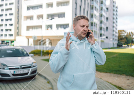 Caucasian confused man disappointed 30s guy millennial male worried stressed car driver near modern auto on city parking outdoors reading bad news mobile phone problem loss upset 119560131