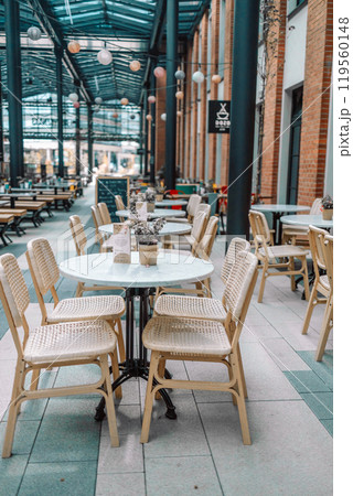 Wooden chairs with a green flowers in the middle of the table of an outdoor restarurant Wooden chairs with a green flowers in the middle of the table of an outdoor restarurant 119560148
