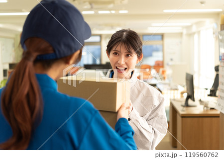 宅配便の荷物を受け取る作業服姿のエンジニアの女性 宅配便の荷物を受け取る作業服姿のエンジニアの女性 119560762