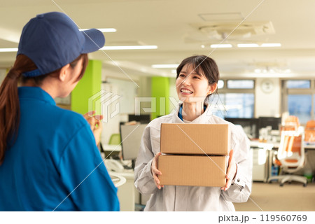 宅配便の荷物を受け取る作業服姿のエンジニアの女性 119560769