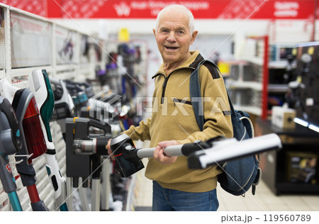 Senor man pensioner buying Upright Vacuum Cleaner in showroom of electrical appliance store 119560789