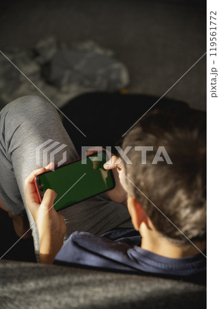 Child looking at phone screen. focus on phone. view from back Child looking at phone screen. focus on phone. view from back 119561772