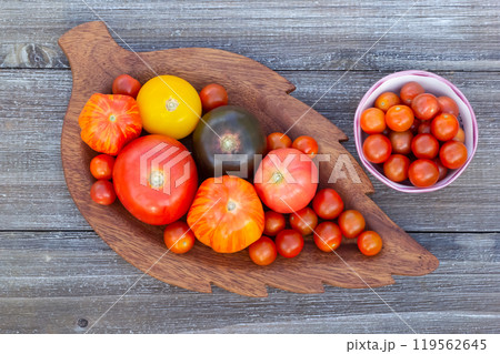 Variety of colorful tomatoes on the wooden plate on the garden table. 119562645