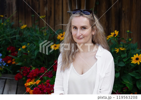 Shy country woman is sitting in the garden bench among flowers. 119563208