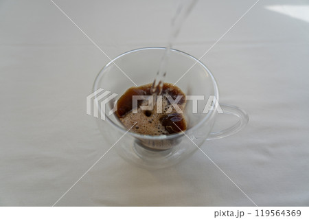 Pouring boiling water into a glass mug with instant coffee. Coffee time Pouring boiling water into a glass mug with instant coffee. Coffee time 119564369