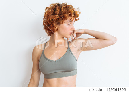 Portrait of a young woman with an athletic build, wearing a sports top, showing off her muscular arms Portrait of a young woman with an athletic build, wearing a sports top, showing off her muscular arms 119565296