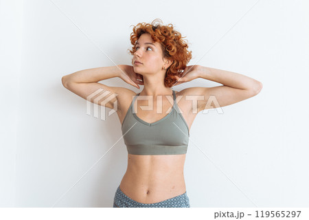 Portrait of a young woman with an athletic build, wearing a sports top, showing off her muscular arms Portrait of a young woman with an athletic build, wearing a sports top, showing off her muscular arms 119565297