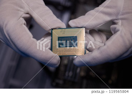 Cropped image of an engineer showing a computer microchip on the foreground 119565804
