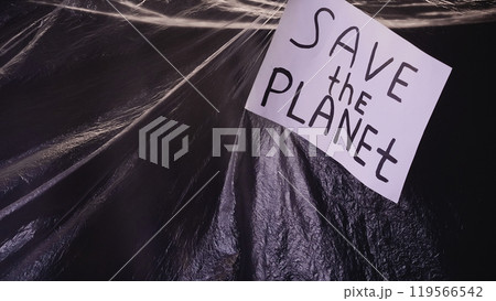 Save planet. Plastic pollution. Ecology problem. Banner with environmental slogan on wrinkled polyethylene film texture dark background. 119566542