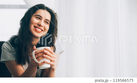 Coffee relaxation. Morning beverage. Weekend rest. Happy satisfied woman in pleasant mood enjoying cup of aromatic drink at window light room copy space. 119566575
