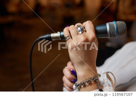 Music artist with body jewelry sings into microphone at concert Music artist with body jewelry sings into microphone at concert 119567107