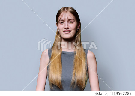 Portrait of beautiful young girl with long blond hair looking at camera on grey background 119567285