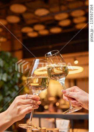 A woman holds a cocktail in her hand, with her fingers wrapped around the glass A woman holds a cocktail in her hand, with her fingers wrapped around the glass 119567364