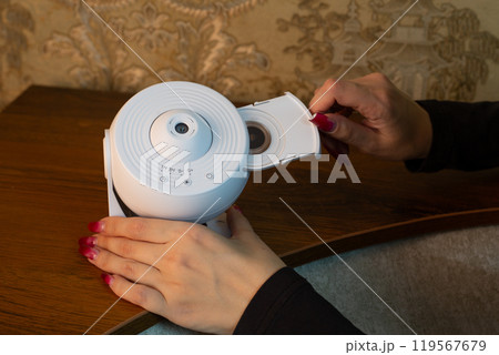 Woman hand inserts film disc into galaxy projector to project starry sky onto the ceiling and study the solar system and deep space, study the planets at home 119567679