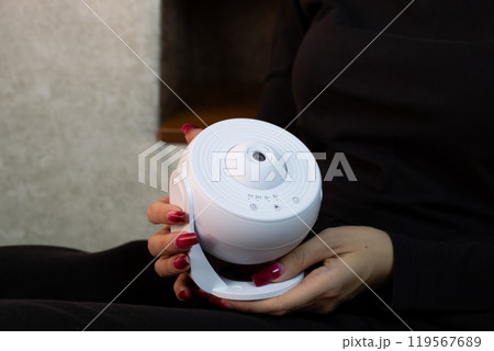 Girl holds in her hands galaxy projector for studying solar system and deep space, compact device for projecting starry sky onto ceiling of room 119567689