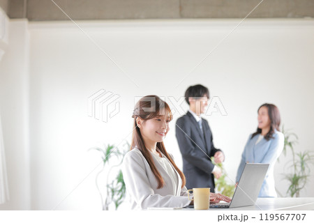 デスクワークする女性と談笑するビジネスパーソン男女_1 119567707