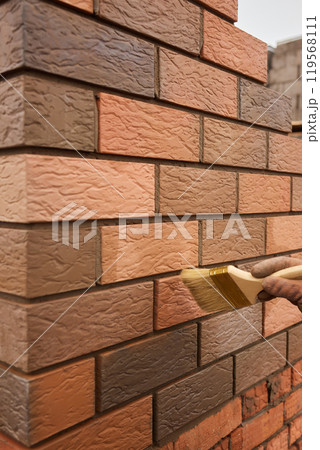 professional construction worker laying bricks and building barbecue in industrial site. Detail of hand adjusting bricks 119568111