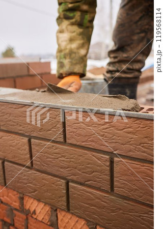 professional construction worker laying bricks and building barbecue in industrial site. Detail of hand adjusting bricks professional construction worker laying bricks and building barbecue in industrial site. Detail of hand adjusting bricks 119568114