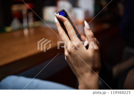 a woman is sitting at a table looking at her cell phone 119568225
