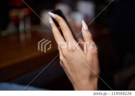 a woman is sitting at a table looking at her cell phone 119568226