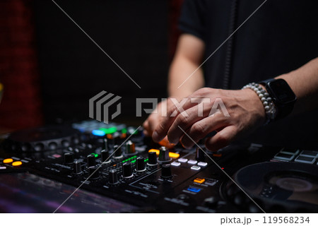 control DJ for mixing music with blurred people dancing at party in nightclub. control DJ for mixing music with blurred people dancing at party in nightclub. 119568234
