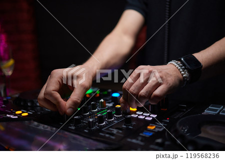 control DJ for mixing music with blurred people dancing at party in nightclub. 119568236