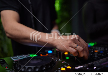 control DJ for mixing music with blurred people dancing at party in nightclub. control DJ for mixing music with blurred people dancing at party in nightclub. 119568249