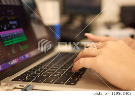 A closeup showing hands typing on a laptop keyboard, with an engagement ring on the finger 119568402