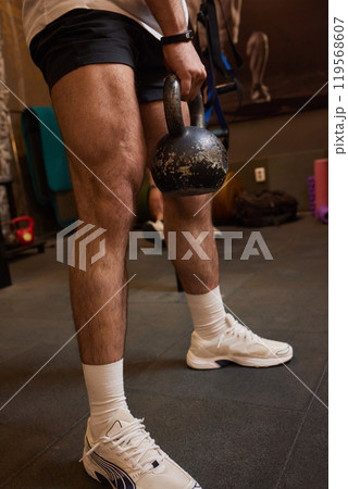 Man is performing a workout in the gym by lifting a kettlebell, focusing on strength and endurance Man is performing a workout in the gym by lifting a kettlebell, focusing on strength and endurance 119568607