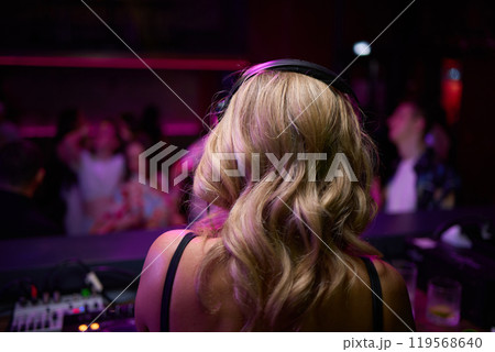 control DJ for mixing music with blurred people dancing at party in nightclub. 119568640