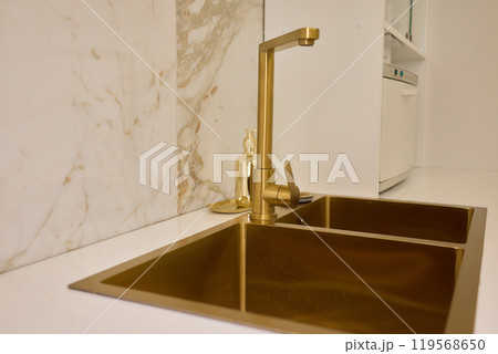 A gold faucet on a bathroom sink with a soap bottle 119568650