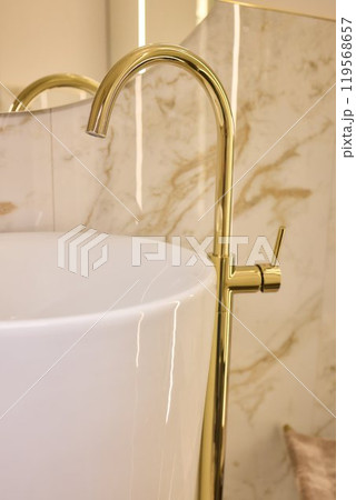 A gold faucet on a bathroom sink with a soap bottle A gold faucet on a bathroom sink with a soap bottle 119568657