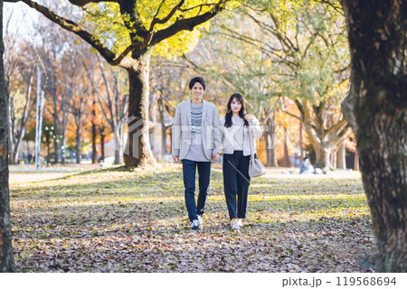 秋の紅葉を楽しみながら公園を散歩するするカップル 119568694