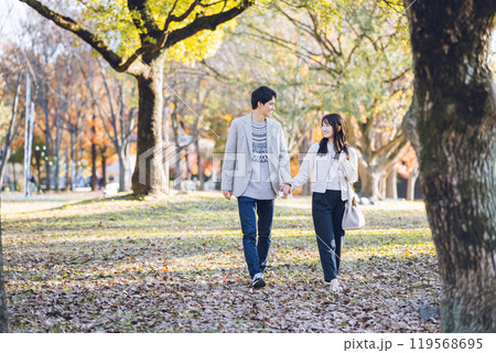 秋の紅葉を楽しみながら公園を散歩するするカップル 119568695