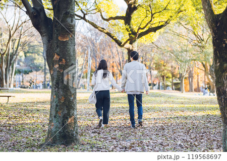 秋の紅葉を楽しみながら公園を散歩するするカップル 119568697