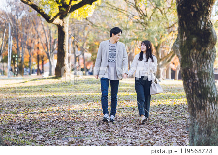 秋の紅葉を楽しみながら公園を散歩するするカップル 119568728
