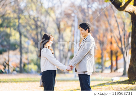 秋の紅葉を楽しみながら公園を散歩するするカップル 秋の紅葉を楽しみながら公園を散歩するするカップル 119568731