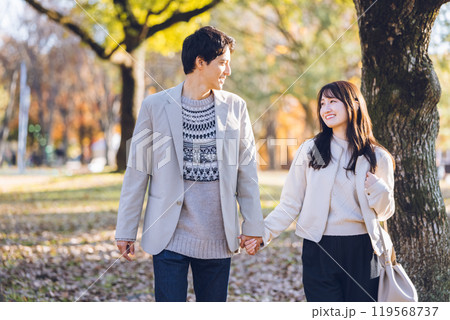 秋の紅葉を楽しみながら公園を散歩するするカップル 秋の紅葉を楽しみながら公園を散歩するするカップル 119568737