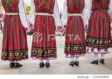 Back view of women in traditional red folk dresses during folk dance performance 119568864