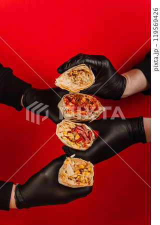 Creative wrap stack held by hands in black gloves, food advertising and street food branding Creative wrap stack held by hands in black gloves, food advertising and street food branding 119569426