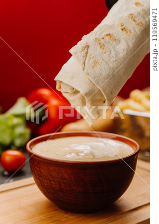 Dipping a wrap into creamy sauce, the perfect blend of flavors for food lovers 119569471