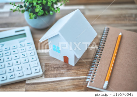 白い住宅模型と電卓と筆記用具 119570045