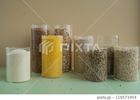 Refillable glass jar with raw grain porridge. Copy space Refill product format eco-friendly living. Filling reusable container Whole spelt grain species. High protein fiber-rich vegan plant based food 119571954