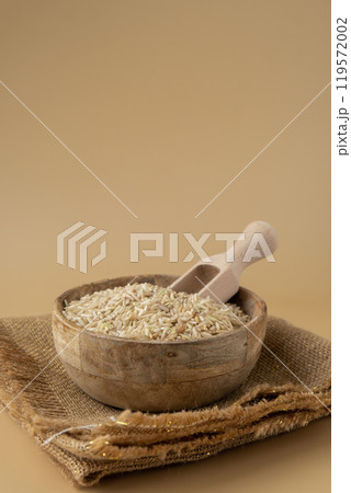 Brown rice in neutral beige background copy space. Whole spelt grain species. High protein fiber-rich vegan plant based food ingredient. Gluten free superfood healthy nutritional dietary alternative 119572002