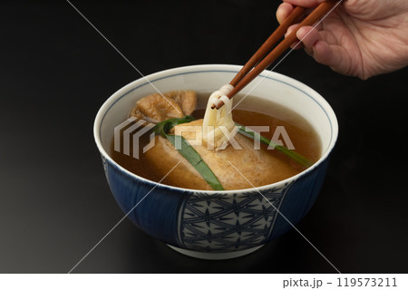 きつねうどん　巾着きつねうどん 油揚げに詰めたうどんを箸で持ち上げる 119573211
